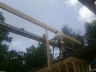 Carpenter setting a ridge beam over a new addition frame — Ice Dam Removal by Roofing Brothers in Corapeake