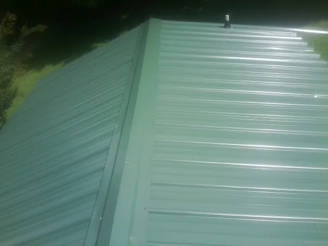 New green metal panels meeting at the ridge of a roof — Flat Roof Repair work by our crew in Corapeake