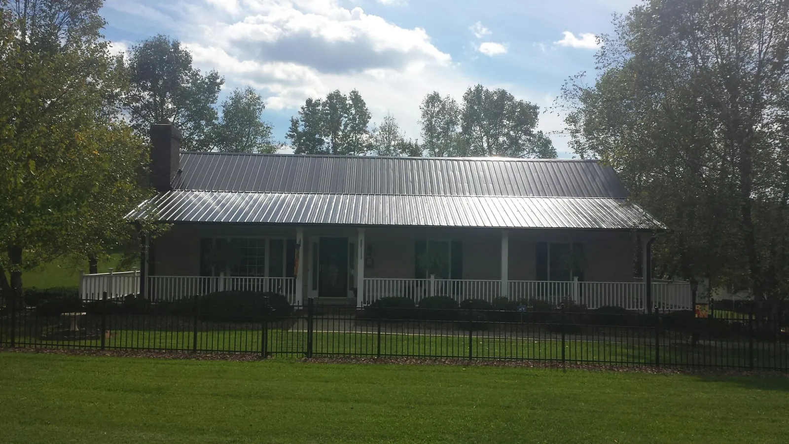 Gray metal roof on a brick ranch with a full width front porch — Gutter Guard Installation work by our crew in Corapeake